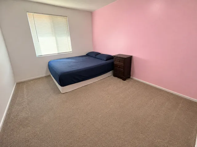 Carpeted flooring throughout, with a window featuring horizontal blinds