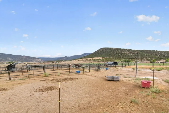 Fenced outdoor area with multiple enclosures and a distant mountainous backdrop