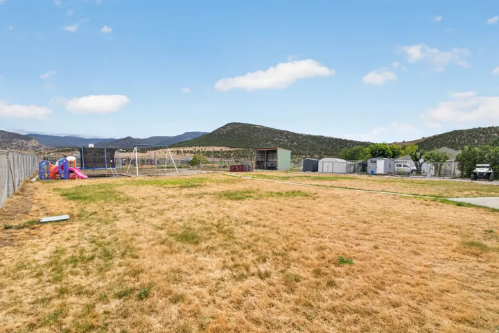 Expansive yard featuring a chain-link perimeter fence and multiple storage structures