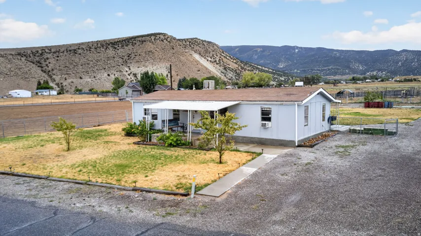 Single-story residence with a covered front porch, concrete walkway, gravel driveway, and a partially fenced yard