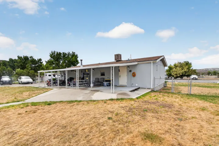 Single-story residence featuring a covered patio, concrete slab, and a chain-link fence