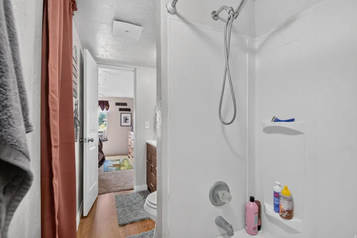 Bathtub with integrated shower, single-handle shower fixture, handheld showerhead, and built-in shelving
