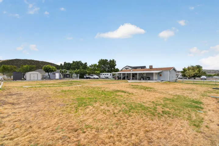 Expansive lot featuring a single-story residence with a covered patio, a detached shed, and a fenced perimeter
