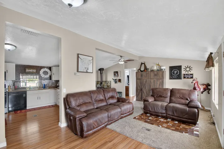 Open-concept living space with vaulted ceilings, wood-finish flooring, and light-colored walls