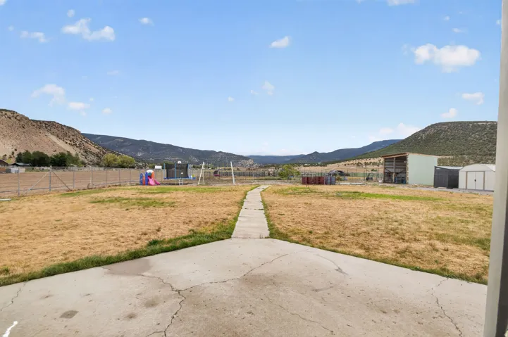 Expansive outdoor space featuring a concrete patio, paved walkway, and distant mountain backdrop