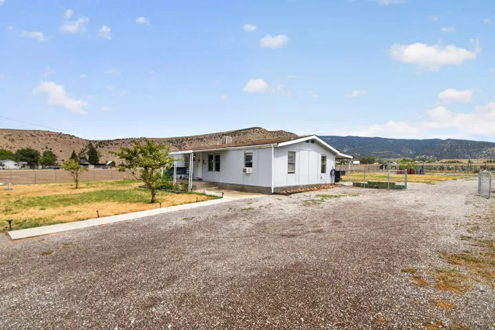 Single-story residence with light-colored siding, a covered front porch, and a gravel driveway