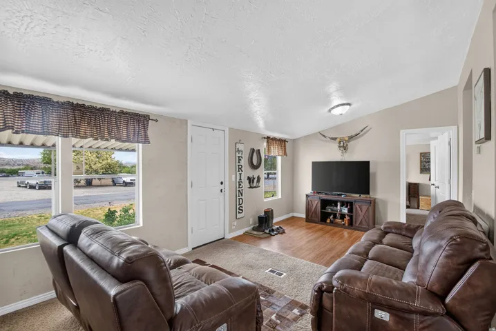 Vaulted ceiling, wood-finish flooring, light neutral wall tones, white trim, and a white interior door