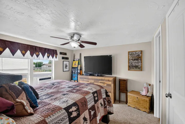 Carpeted flooring, window with blinds, ceiling fan with integrated lighting, door with hardware