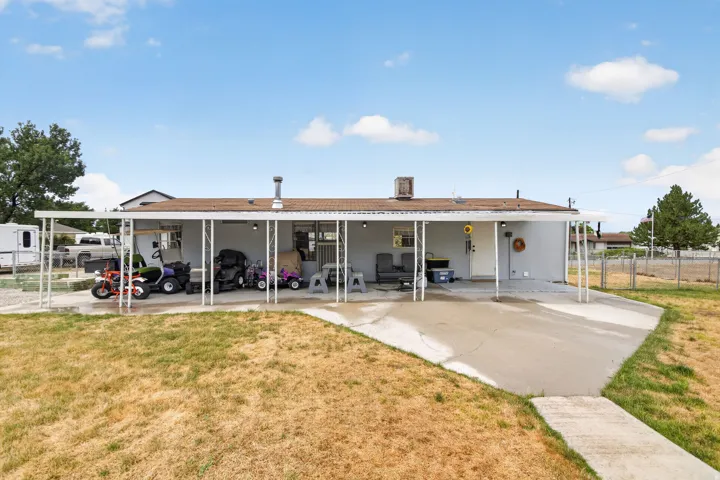 Rear exterior featuring an extended covered patio, concrete patio surface, and a partially fenced yard