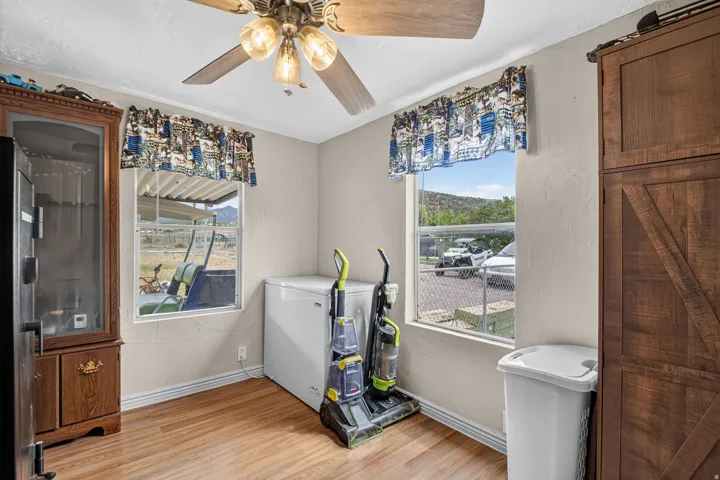 Light-toned walls with wood-finish flooring, two windows, and a ceiling fan with integrated lighting