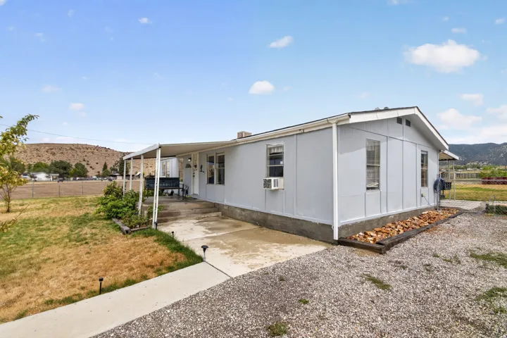 Light gray exterior with white trim, covered front patio, concrete walkway, and gravel landscaping