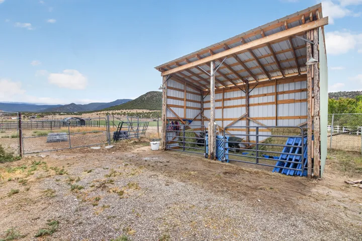 Metal-sided shed with wood frame construction, featuring a sloped roof and open-air design
