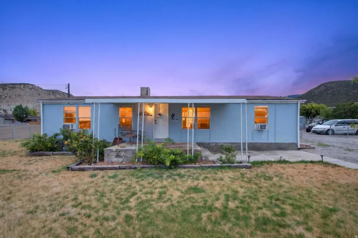 Single-story light blue exterior with multiple windows and a covered front porch