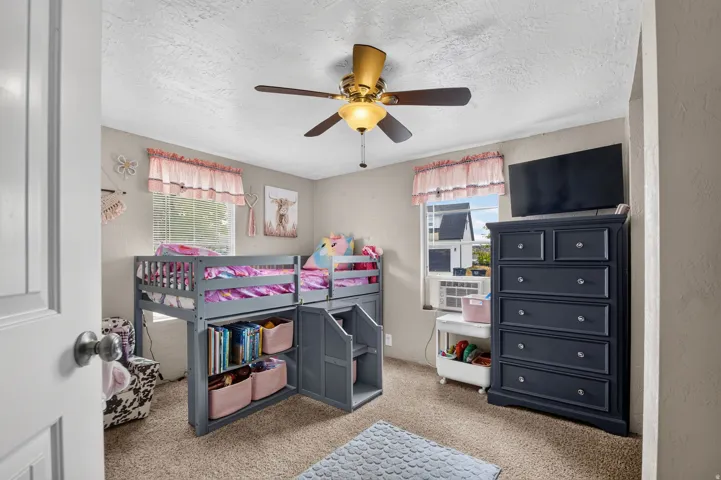 Carpeted room with a ceiling fan and window