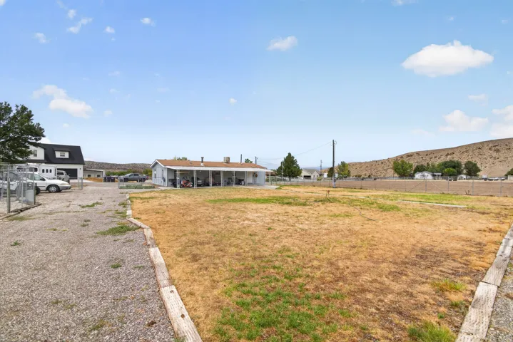 Expansive outdoor area with a gravel driveway, fenced perimeter, and a detached structure with a garage door