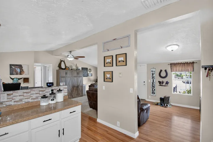 White cabinetry with dark hardware, stone-finish countertops, and a mosaic tile backsplash