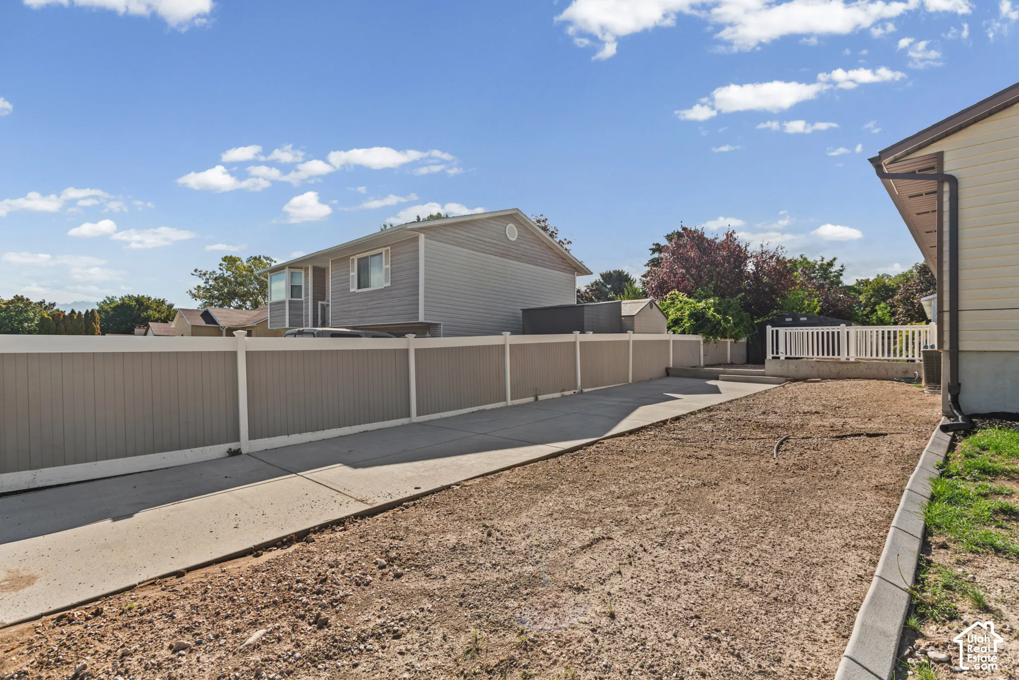 Concrete driveway leading to a fenced-in property with a patio area
