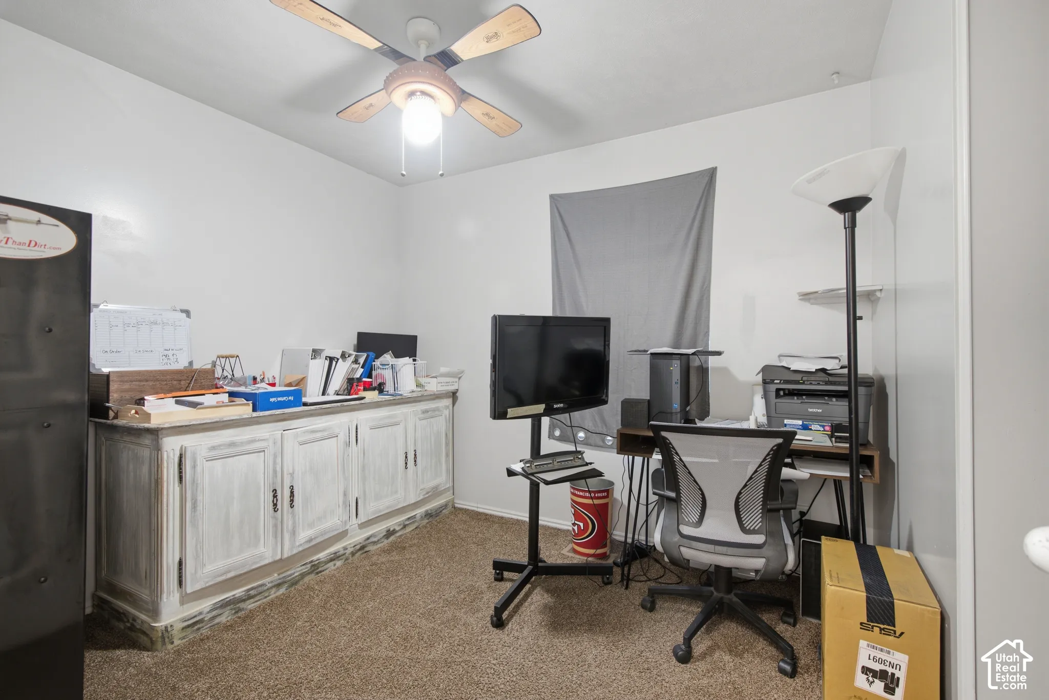 Built-in cabinetry with a distressed finish, textured carpeting, and a ceiling fan with light fixture