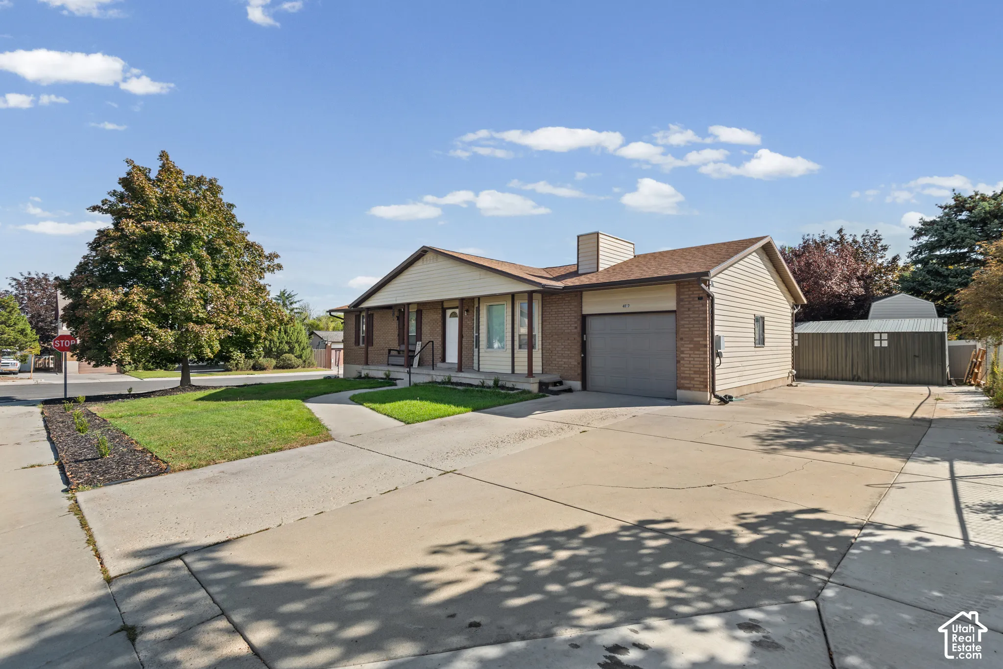 Exterior featuring a paved driveway, attached garage, and a built-in storage shed