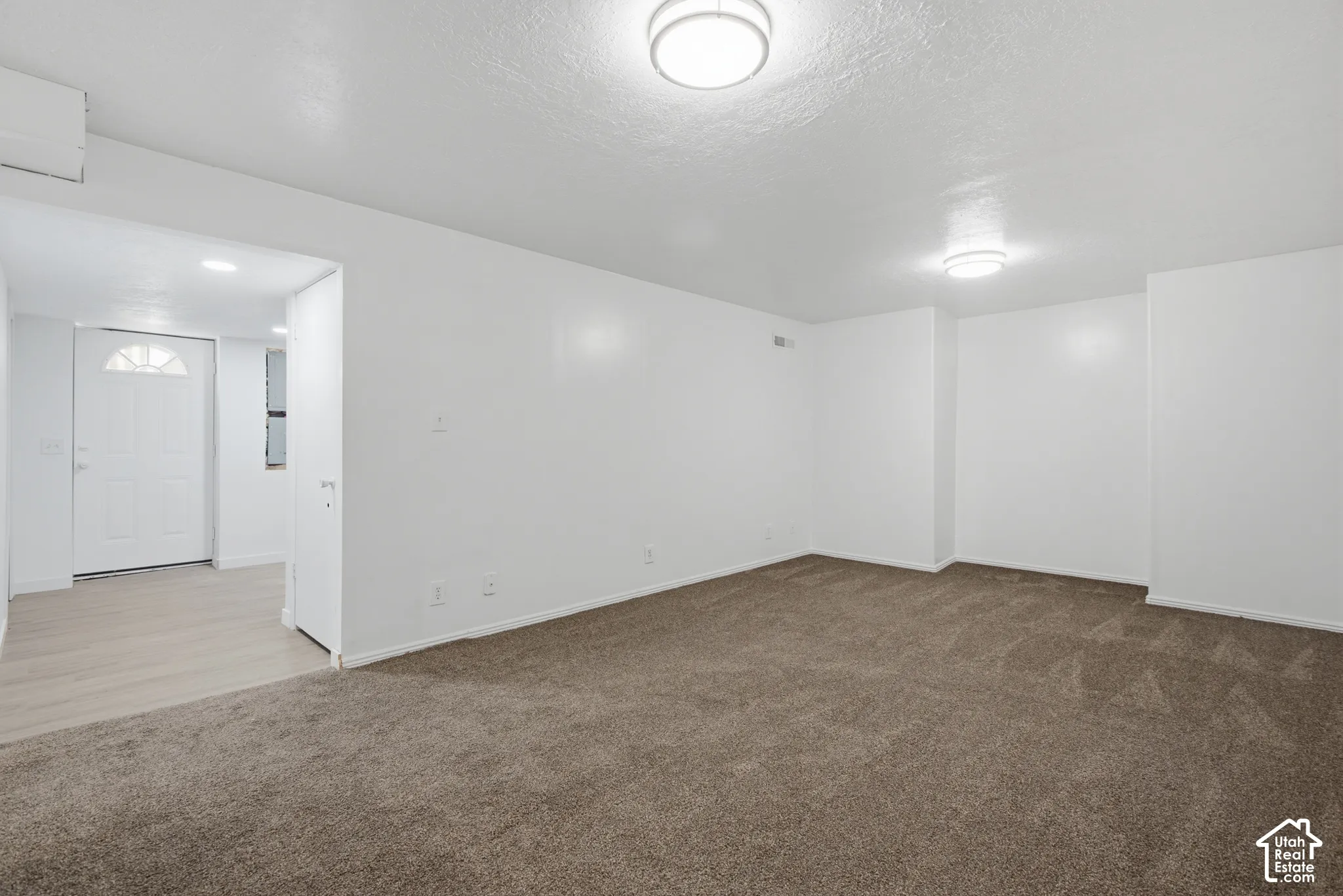 Spacious room with plush carpeting, neutral white walls, and two ceiling-mounted light fixtures