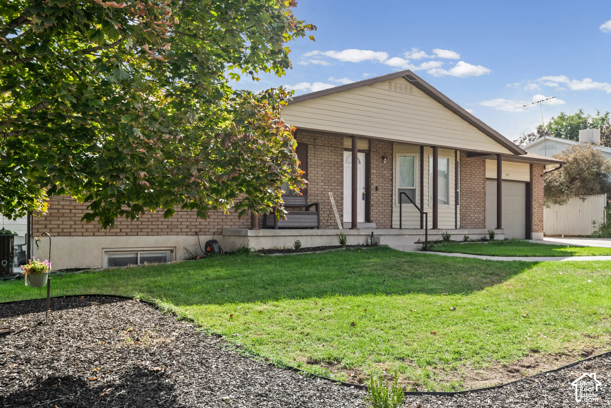 Brick exterior with a gabled roofline, covered entry, attached garage, and a concrete driveway