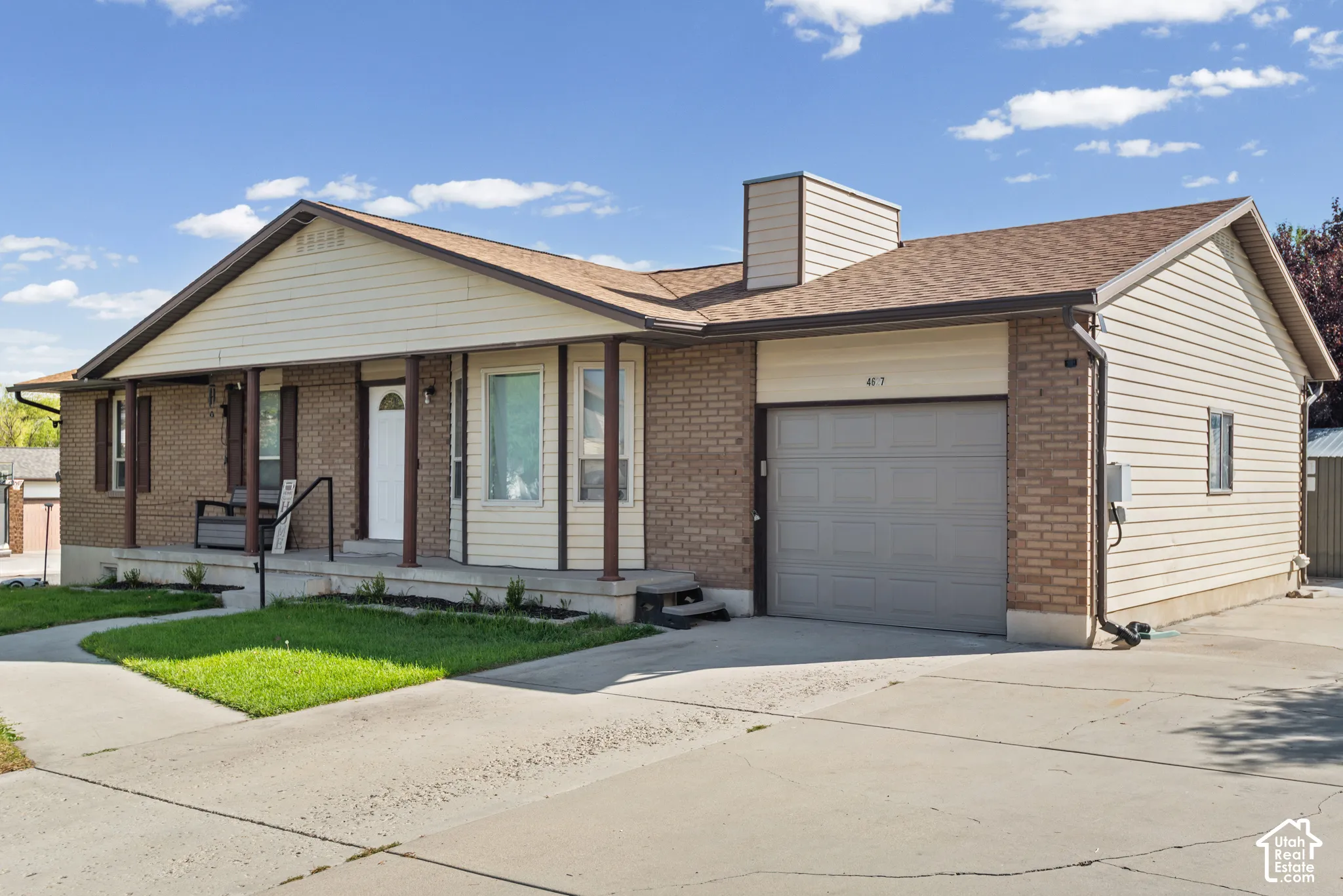 Brick and siding exterior with covered porch, attached garage, and concrete driveway