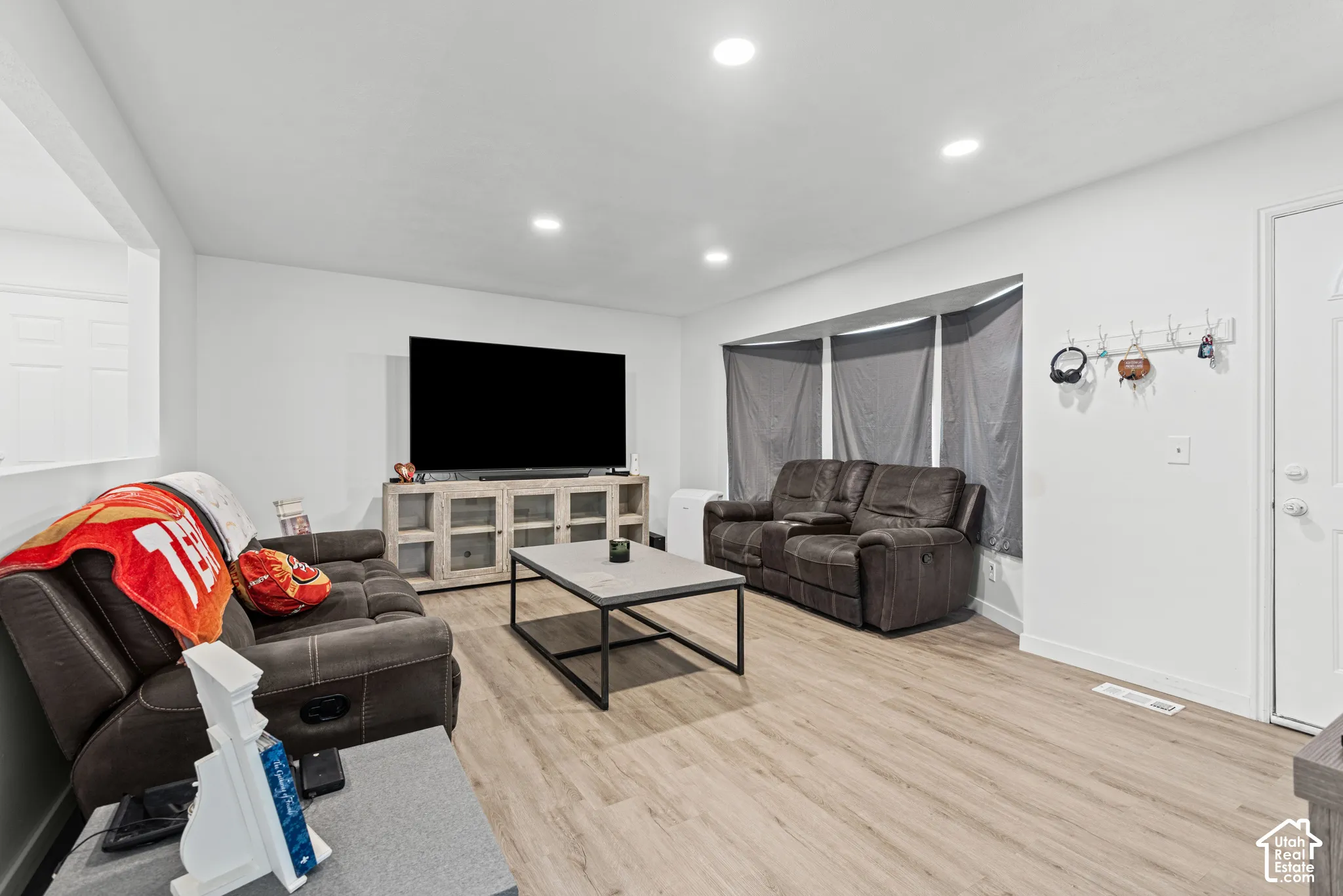 Recessed lighting, wood-finish flooring, white paneled door, and a bay window