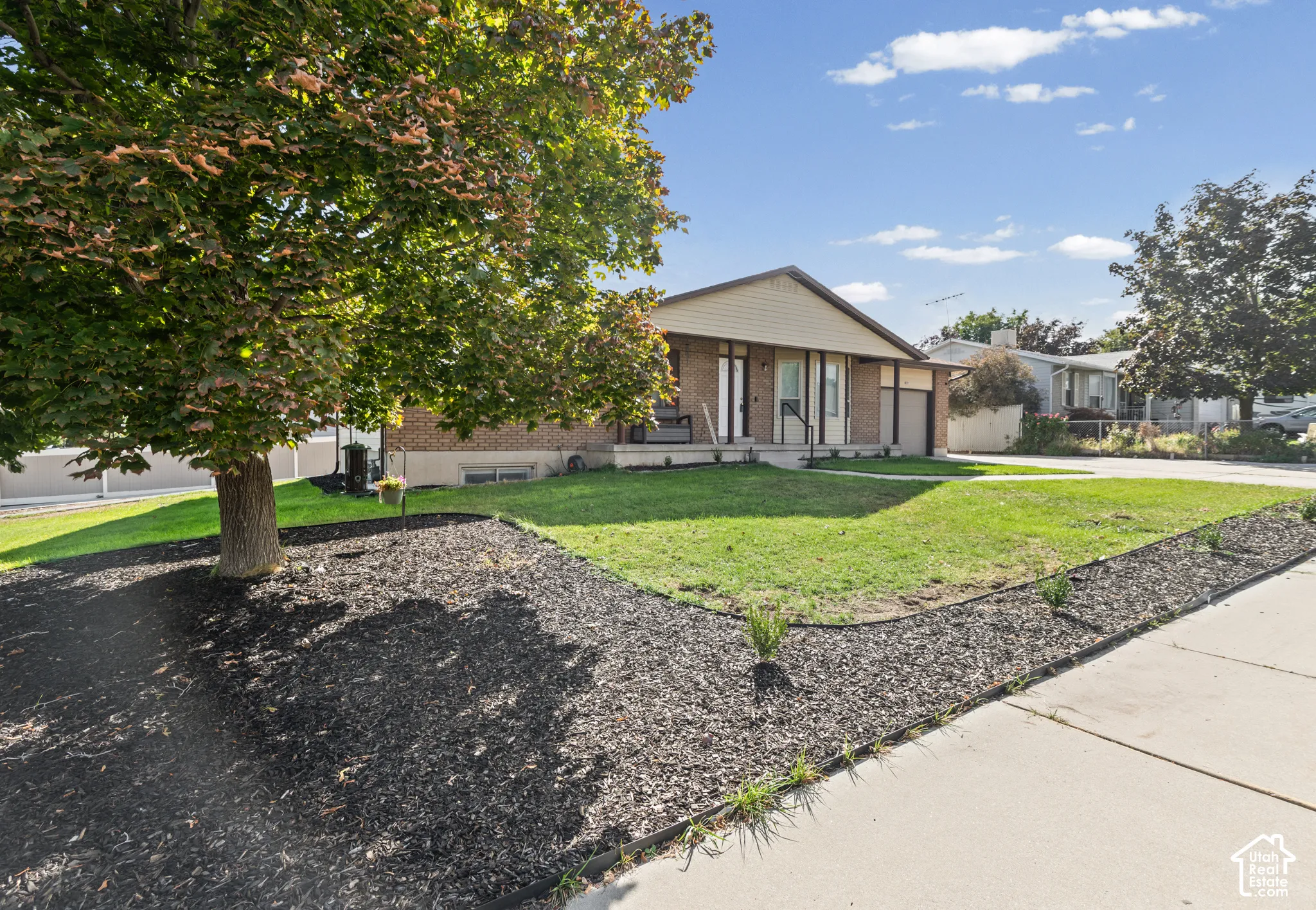 Brick facade, attached garage, well-maintained lawn, mature tree, established landscaping