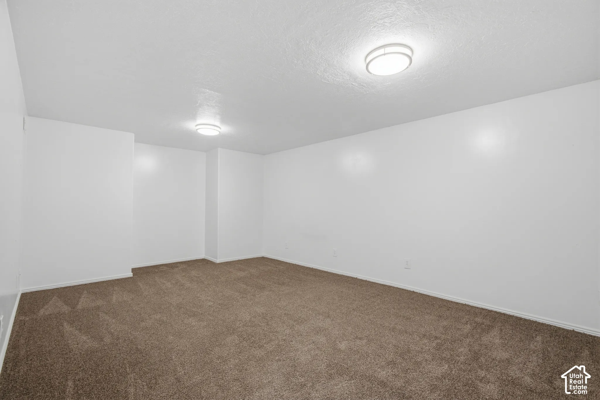 Neutral white wall paint, two ceiling-mounted circular light fixtures, and brown carpeting