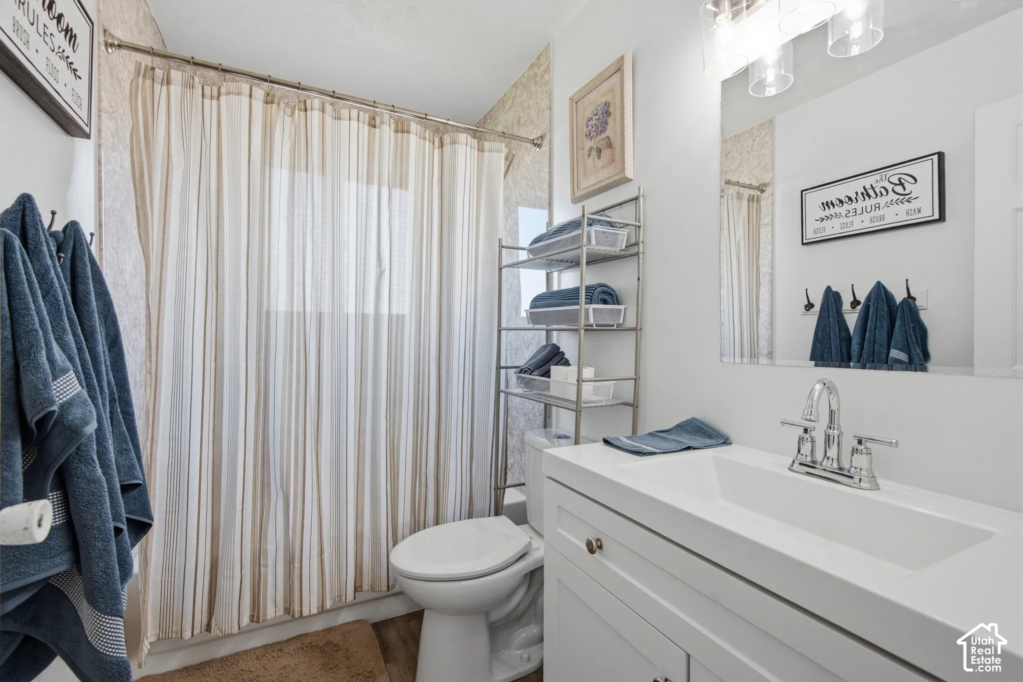 White vanity with integrated sink, chrome faucet, wall-mounted mirror, and overhead vanity lighting