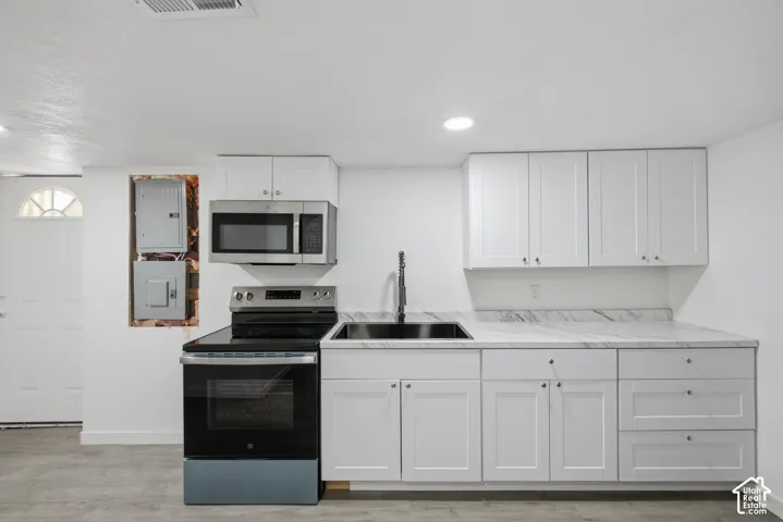 White shaker cabinetry, stone-finish countertops, stainless steel appliances, recessed lighting, and a modern black sink with a gooseneck faucet
