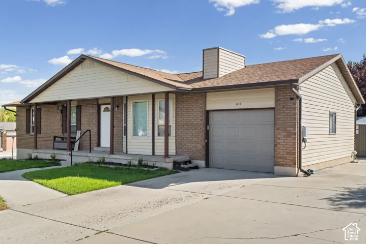 Brick and siding exterior with covered porch, attached garage, and concrete driveway