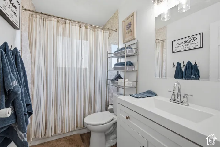 White vanity with integrated sink, chrome faucet, wall-mounted mirror, and overhead vanity lighting
