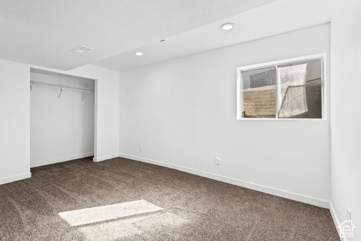 Carpeted flooring, recessed lighting, white walls, built-in closet with wire shelving, and a window