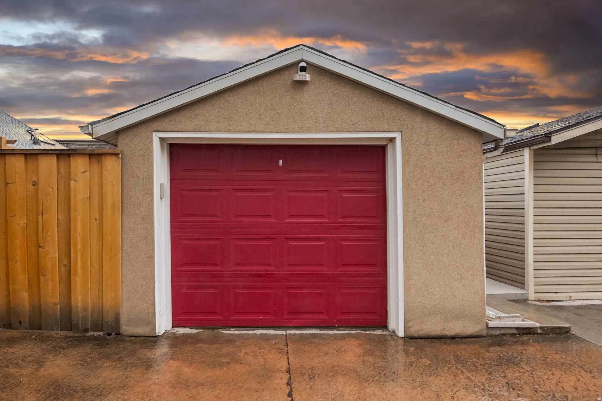 Detached garage with a red panel door and stucco exterior