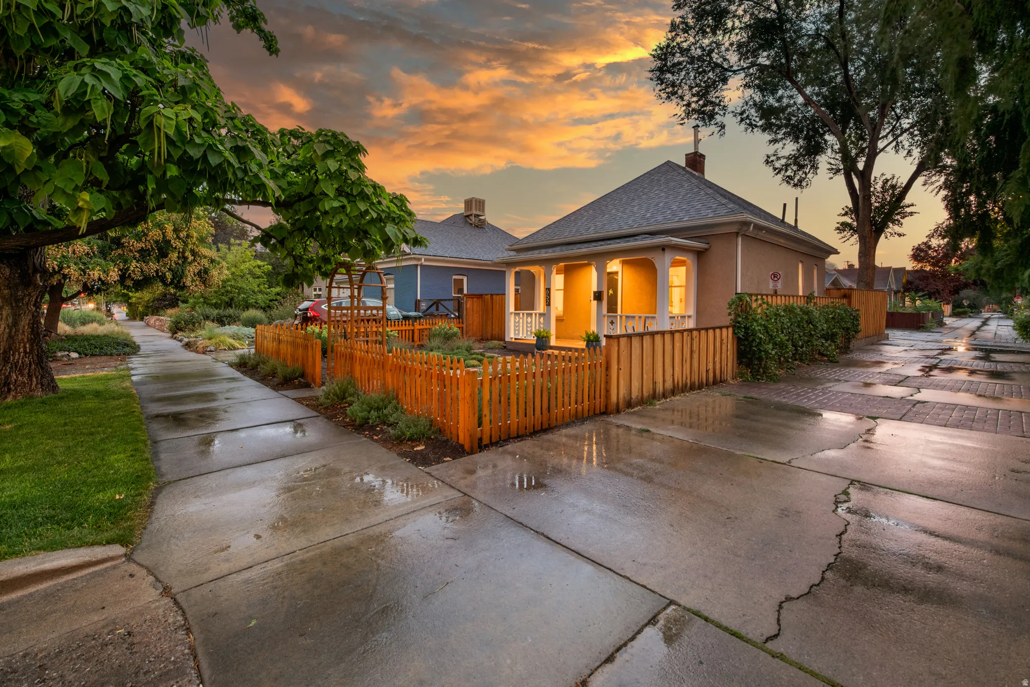 Inviting front porch with columns, a wood picket fence, and established landscaping