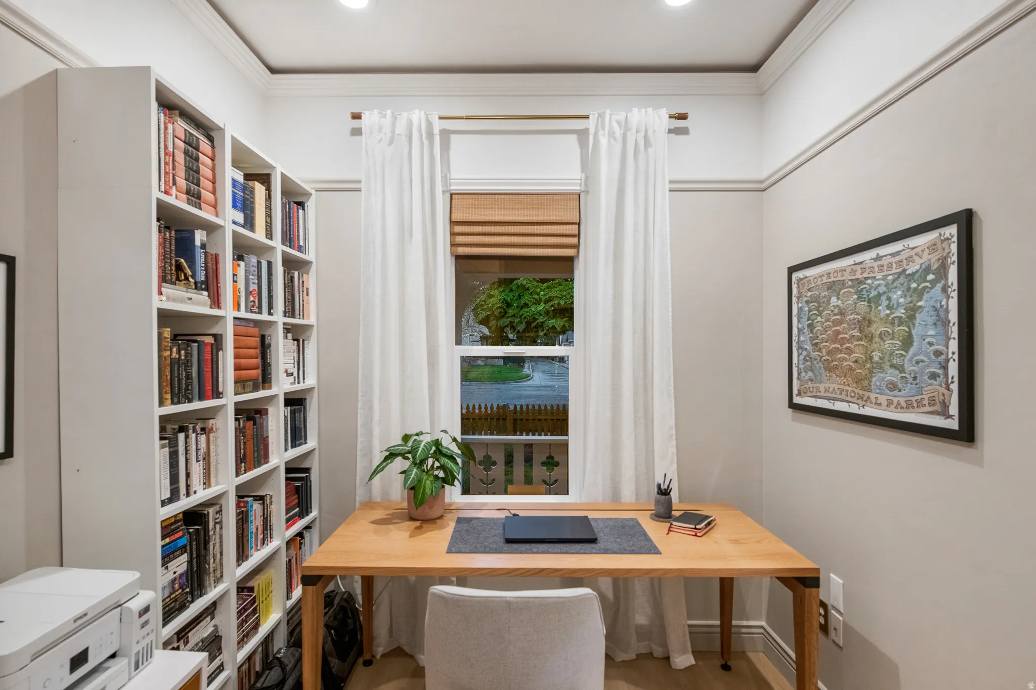 Built-in shelving, crown molding, recessed lighting, wood-finish flooring, and a large window with window treatments