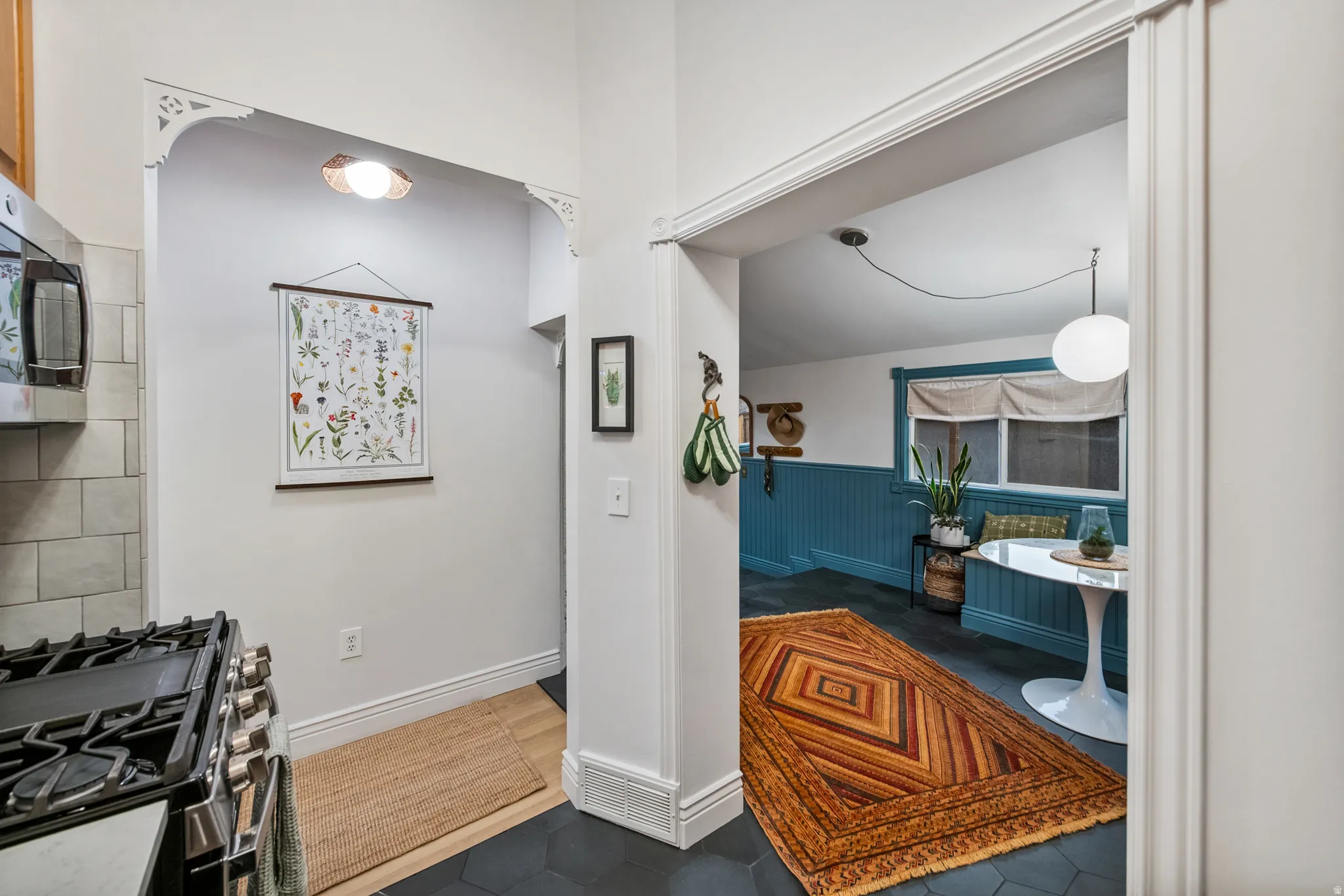Arched doorway with decorative corbels, stainless steel range with griddle, white subway tile backsplash, and hexagonal floor tile
