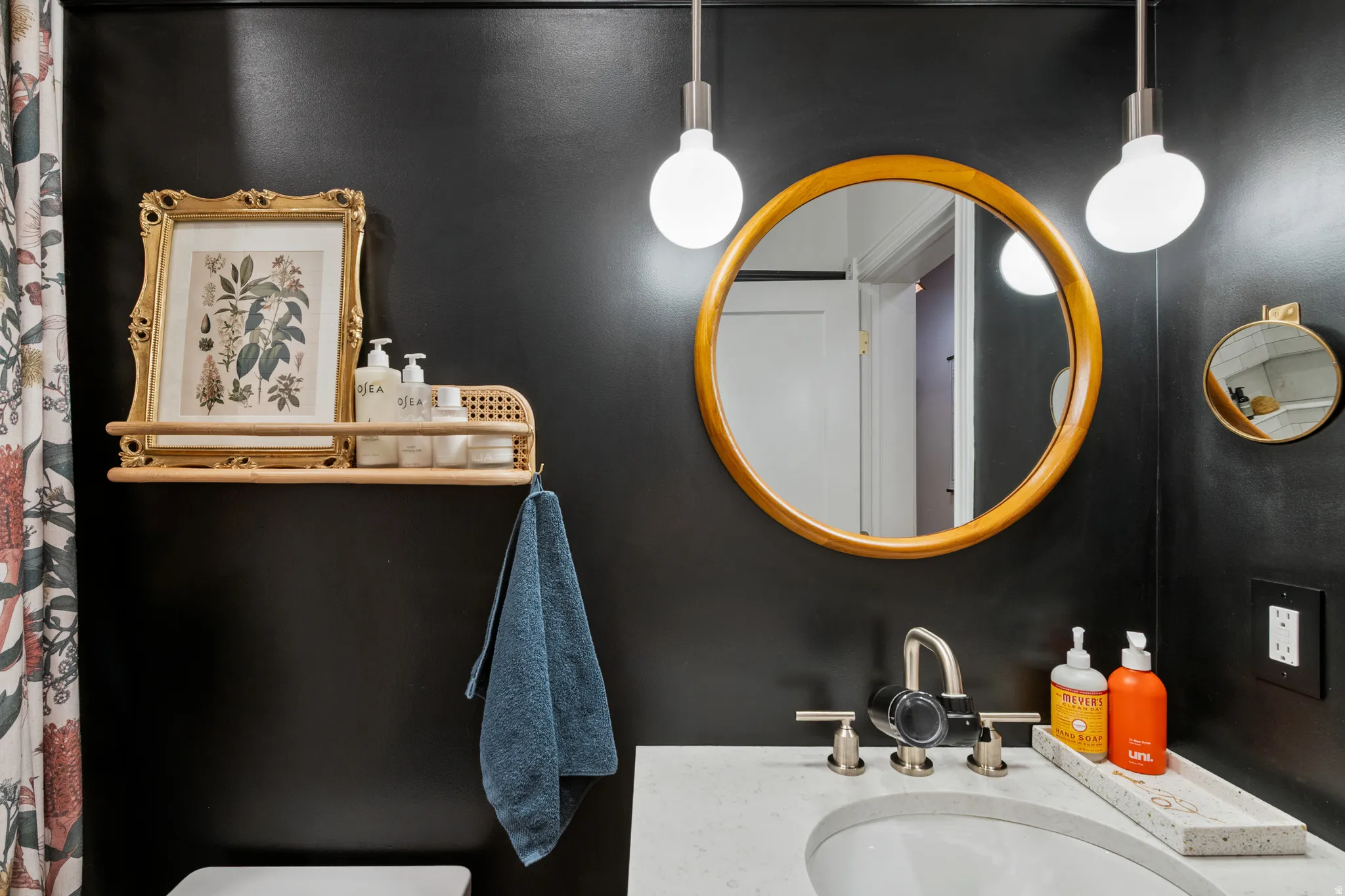 Integrated vanity sink with a white countertop, brushed nickel faucet, and a round wooden mirror