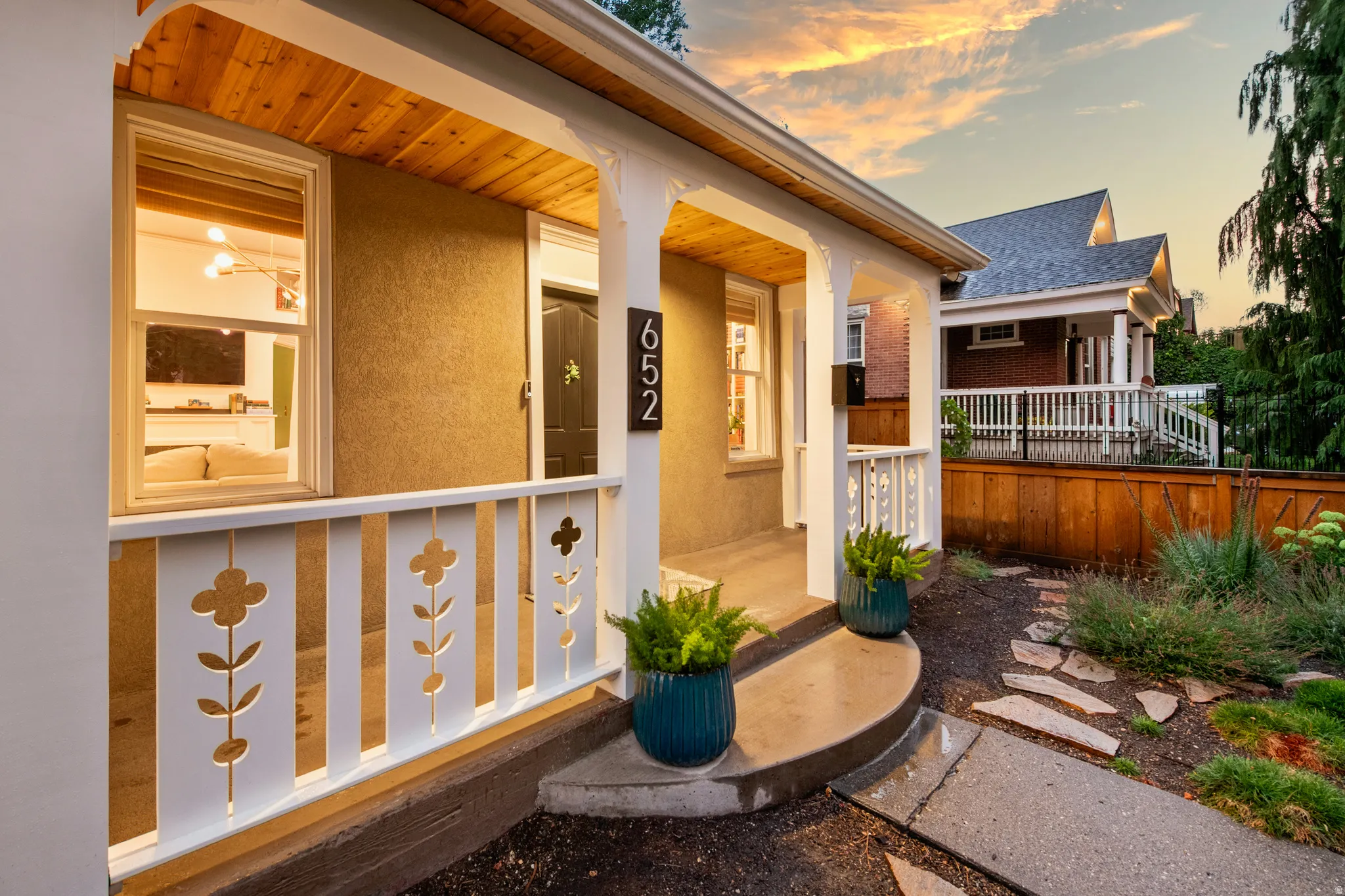 Covered front porch with a wood-finish ceiling, decorative railing, and stucco exterior