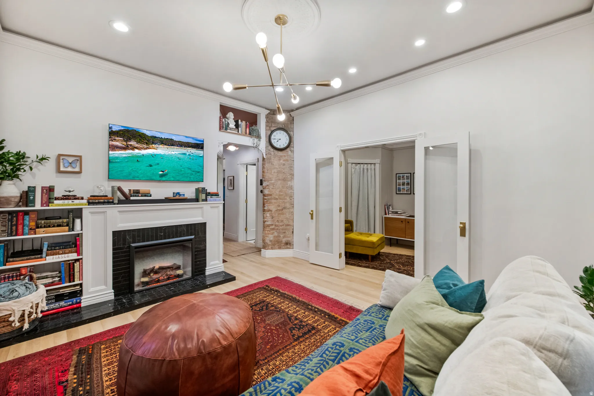 Built-in shelving flanking a black-tiled fireplace with a white mantel, recessed lighting, crown molding, and wood-finish flooring