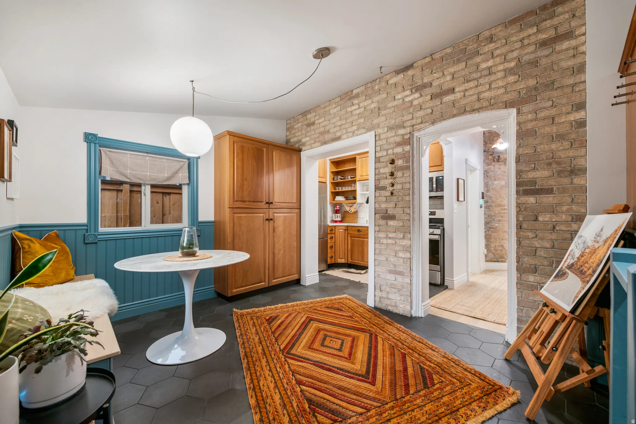 Exposed brick wall, built-in cabinetry, hexagonal floor tiling, architectural window trim, and pendant lighting