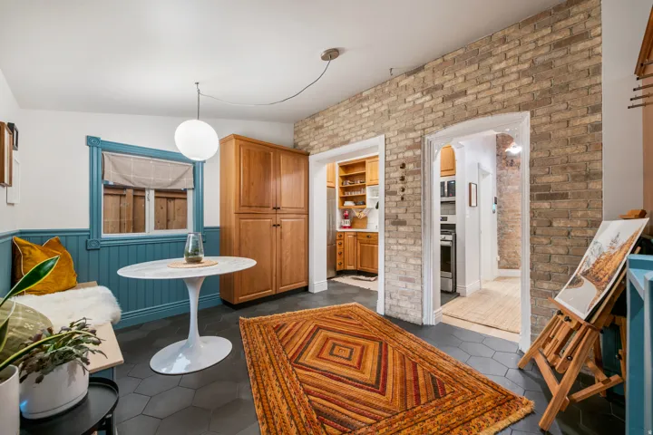 Exposed brick wall, built-in cabinetry, hexagonal floor tiling, architectural window trim, and pendant lighting