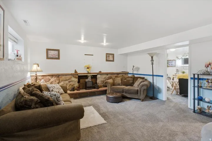 Carpeted flooring, recessed lighting, and a stone-clad fireplace with a hearth