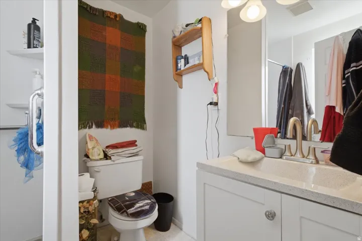 Bathroom featuring a white toilet, shower with glass door, and a vanity with an integrated sink and brushed nickel faucet