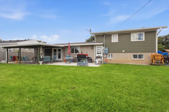 Expansive green lawn with a covered patio, featuring a concrete surface and direct exterior access