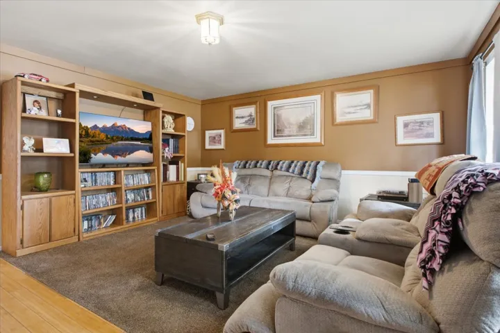 Living room with ceiling-mounted light fixture, and carpeted flooring.