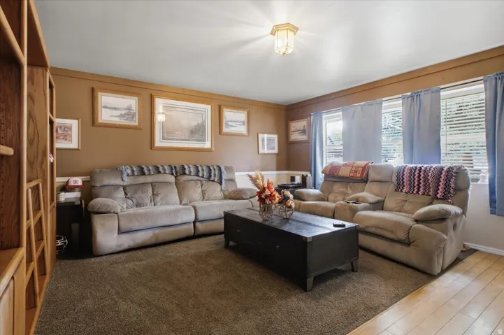 Living room with ceiling-mounted light fixture, and carpeted flooring.