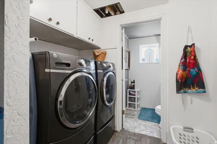 Laundry area with built-in cabinetry and shelving, front-loading washer and dryer, and tile-finish flooring