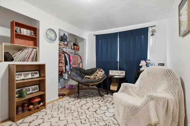Bedroom with an open closet with built-in organization, and wood-finish flooring
